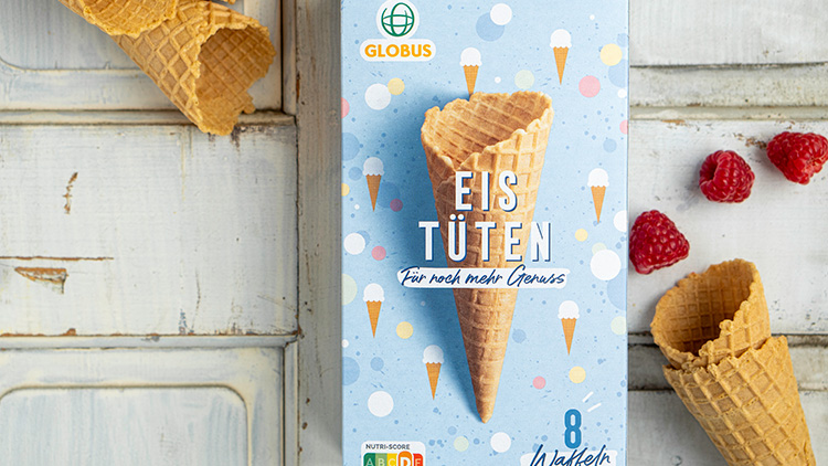 Verpackung mit der Aufschrift „EISTÜTEN Für noch mehr Genuss“, daneben liegen Waffelhörnchen und frische Himbeeren.