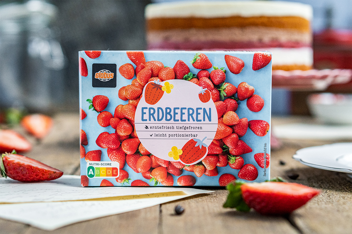 Eine Packung GLOBUS Erdbeeren mit Aufschrift „erntefrisch tiefgefroren, leicht portionierbar“ und Nutri-Score A auf Holztisch.