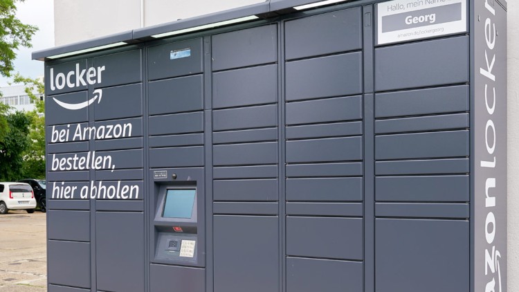 Dunkelgrauer Amazon Locker mit Bildschirm, Tastenfeld und dem Text „bei Amazon bestellen, hier abholen“.