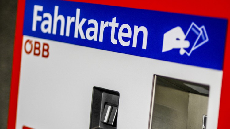 Roter Fahrkartenautomat mit blauem Schild „Fahrkarten“, ÖBB-Logo und Karten-Symbol, Kartenschlitz und Ausgabefach sichtbar.