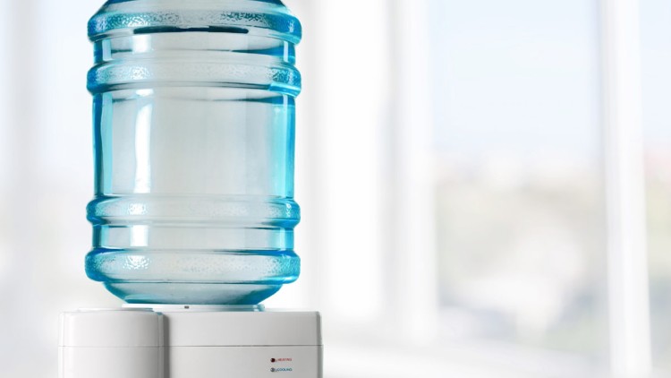 Ein Wasserbehälter aus durchsichtigem blauem Kunststoff steht umgedreht auf einem weißen Wasserspender mit zwei Kontrollleuchten.
