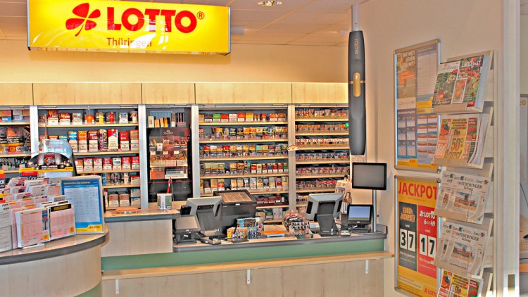 Lottoannahmestelle mit beleuchtetem „LOTTO Thüringen“-Schild, Zeitungsständer, Theke, Kassensystem und Verkaufsregalen.