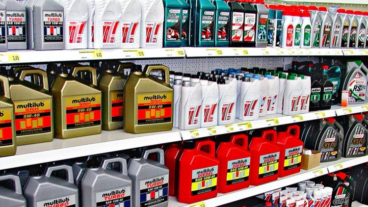 Regale mit verschiedenen Motorölen in Kanistern und Flaschen, darunter Marken wie Multilub und Castrol, mit Preisschildern.