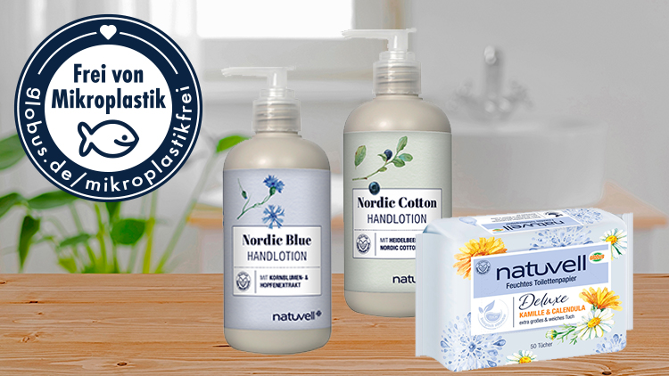 Zwei Spender Handlotion und eine Packung feuchtes Toilettenpapier stehen auf einem Holzuntergrund, daneben ein Siegel mit „Frei von Mikroplastik“.
