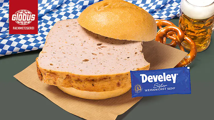 Eine Leberkässemmel mit Develey süßem Weißwurst-Senf, einer Brezel und einem Bier, dekoriert mit einer blau-weißen Tischdecke.