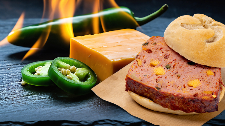 Brot mit Fleischkäse, grünen Jalapeños und Käse neben einer brennenden Chili, frischen Jalapeños und einem Käsestück.