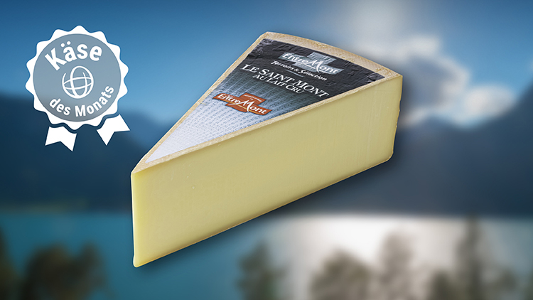 Ein Stück gelblicher Käse mit der Aufschrift „Le Saint Mont“, daneben das weiße Emblem „Käse des Monats“.