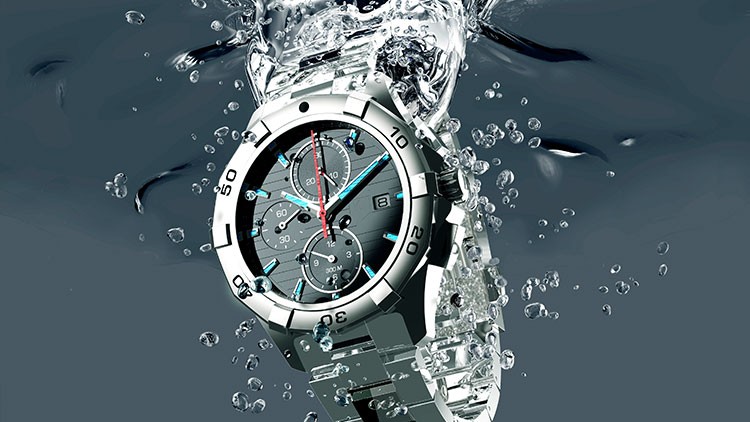 Eine silberne Armbanduhr mit Chronographen-Funktion und blau-roten Akzenten taucht ins spritzende Wasser ein.