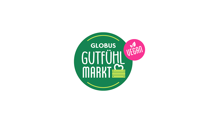 Grünes rundes Logo mit „GLOBUS Gutfühl Markt“ in Weiß, darunter eine grüne Holzkiste mit Herz, pinker Kreis mit „Vegan“.