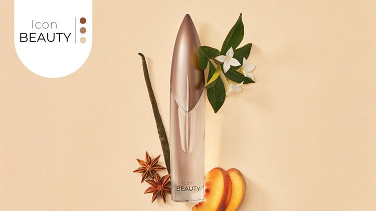 Goldenes Parfümflakon mit Schriftzug Icon BEAUTY, umringt von Sternanis, Vanilleschote, Pfirsichscheiben und weißen Blüten.