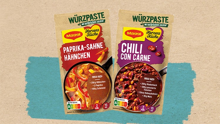Zwei Maggi-Würzpastenpackungen mit den Sorten Paprika-Sahne-Hähnchen und Chili con Carne vor beigem Hintergrund mit blauem Akzent.