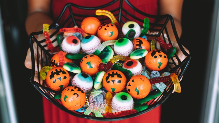 Schwarze Schale in Spinnennetzoptik, gefüllt mit orangefarbenen Kürbis-Süßigkeiten, Augapfel-Bonbons und Gummi-Würmern.