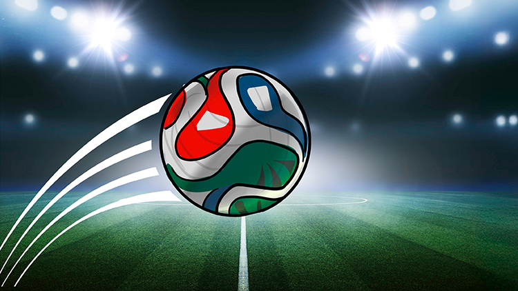 Ein bunt gestalteter Fußball fliegt auf einem beleuchteten Fußballfeld mit grünem Rasen in Richtung Torlinie.
