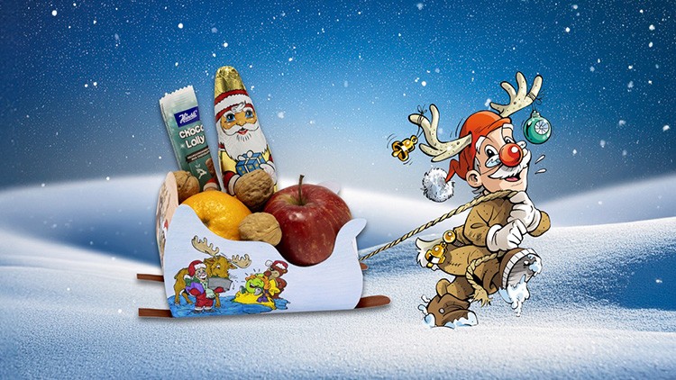 Ein bunt bemalter Schlitten mit Äpfeln, Nüssen, Mandarinen und Süßigkeiten wird von einem Rentier-Maskottchen im Schnee gezogen.