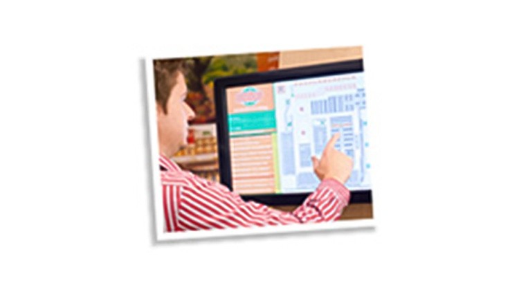 Eine Person in einem rot-weiß gestreiften Hemd bedient einen Touchscreen mit einem Lageplan von GLOBUS.