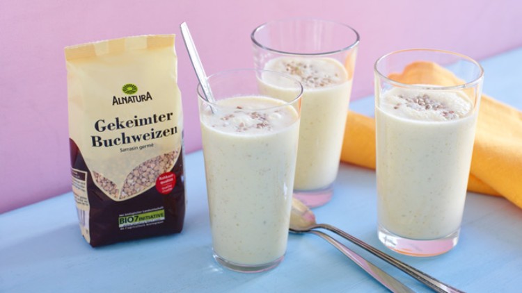 Drei Gläser mit gelblichem Smoothie, bestreut mit Buchweizen, stehen neben einer Alnatura-Packung „Gekeimter Buchweizen“.