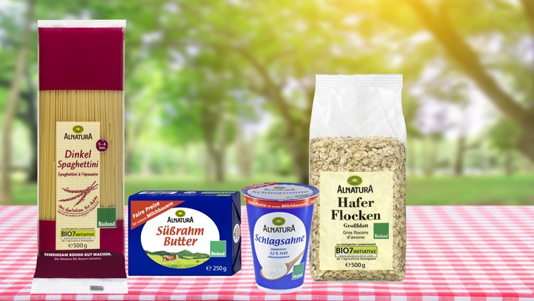 Alnatura-Produkte, darunter Dinkel-Spaghettini, Süßrahmbutter, Schlagsahne und Haferflocken, auf rot-weißem Tischtuch.