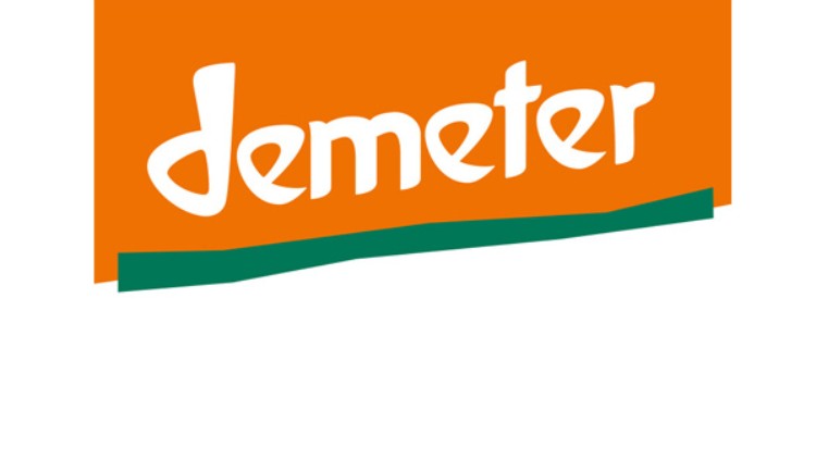 Das Bild zeigt das orange-weiße Logo von Demeter mit grünem Balken am unteren Rand.