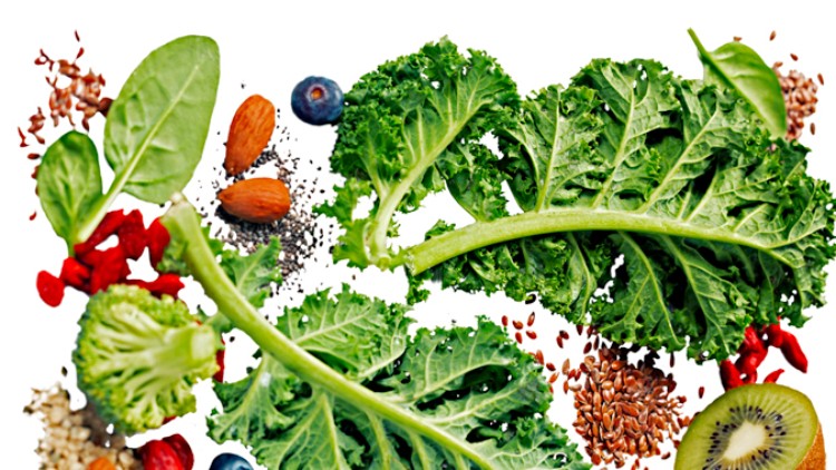 Grünkohlblätter, Brokkoli, Kiwi, Blaubeeren, Mandeln, Leinsamen, Gojibeeren und Spinatblätter auf weißem Hintergrund.