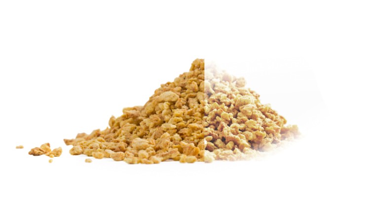 Ein Haufen goldgelber, kleiner, unregelmäßig geformter Cerealienstückchen auf weißem Hintergrund.