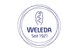 Blau-weißes Logo mit dem Schriftzug WELEDA, einer stilisierten Pflanze und dem Text „Seit 1921“ in einem Kreis aus Linien.