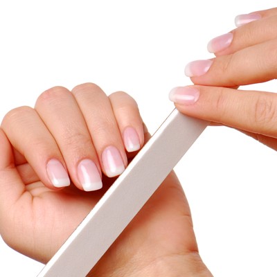 Eine Hand mit gepflegten Nägeln feilt mit einer weißen Nagelfeile an der anderen Hand.