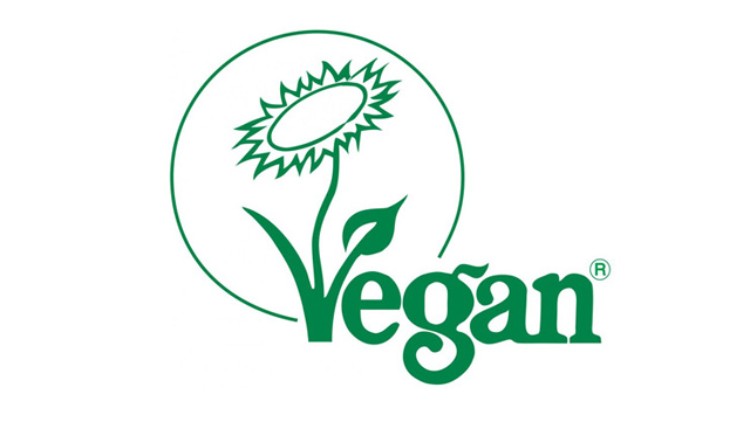Grünes Logo mit gezeichneter Sonnenblume und dem Wort „Vegan“ in geschwungener Schrift, eingekreist von einer Linie.