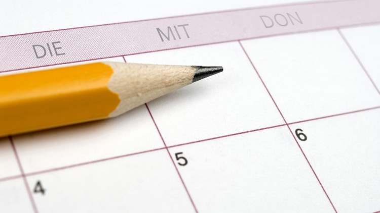 Ein spitzer gelber Bleistift liegt auf einem Kalender, der die Wochentage „DIE“, „MIT“ und „DON“ sowie Zahlen zeigt.