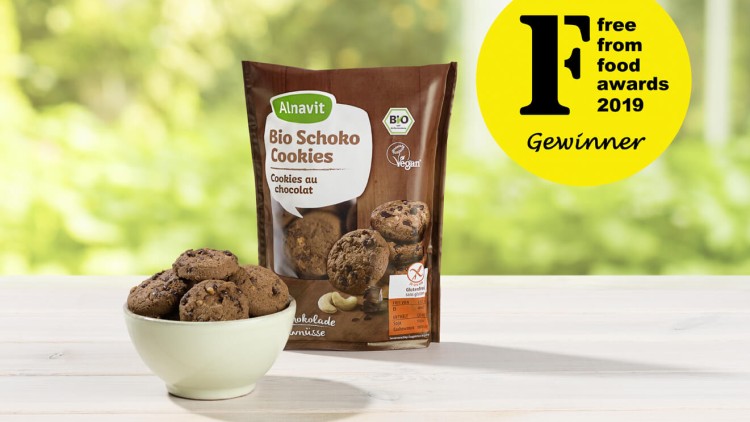 Auf einem Holztisch steht eine Schale mit Cookies vor einer Alnavit-Verpackung und einem gelben „free from food awards 2019“-Siegel.