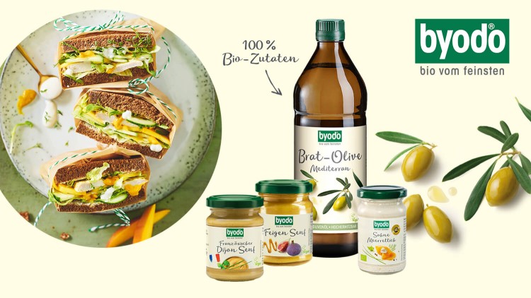 Drei Sandwiches mit Salat und Saucen auf einem Teller, daneben Produkte von byodo wie Senf, Meerrettichcreme und Brat-Olive-Öl.