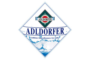 Ein blau-weißes Logo mit der Aufschrift „ADLDORFER“ und „Größter Mineralbrunnen aus Bayern“, darunter spritzendes Wasser.