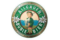 Rundes Logo mit goldenem Rand, Text „Allgäuer Büble Bier“, Illustration eines Kindes mit Krug und Alpenlandschaft im Hintergrund.