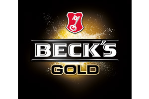 Schwarzer Hintergrund mit goldenem Lichtstrahl, zentral der weiße Schriftzug „BECK'S GOLD“, darüber rotes Wappen mit Schlüssel.