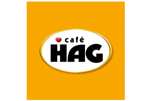 Weißer ovaler Hintergrund mit rotem Herz und schwarzer Schrift „café HAG“ auf orangefarbenem Hintergrund.