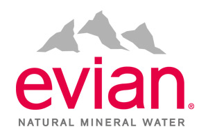 Weißer Hintergrund mit grauen Bergen darüber der rote Schriftzug „evian“, darunter „NATURAL MINERAL WATER“ in schwarzer Schrift.