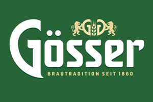 Weißer Schriftzug „Gösser Brautradition seit 1860“ mit goldenen Löwen und Hopfenmotiv auf grünem Hintergrund.