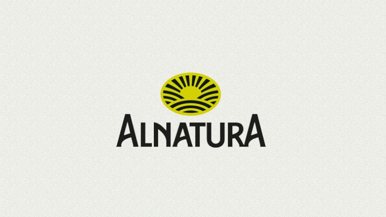 Gelbes Symbol einer Sonne mit Strahlen und geschwungenen Linien darüber der schwarze Text „ALNATURA“ auf hellem Hintergrund.