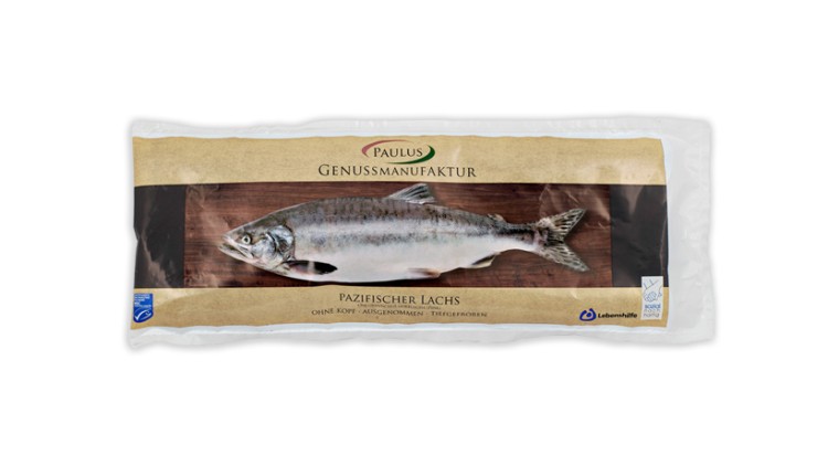 Verpackung mit tiefgefrorenem pazifischen Lachs ohne Kopf, Marke Paulus Genussmanufaktur, auf braunem Hintergrund.