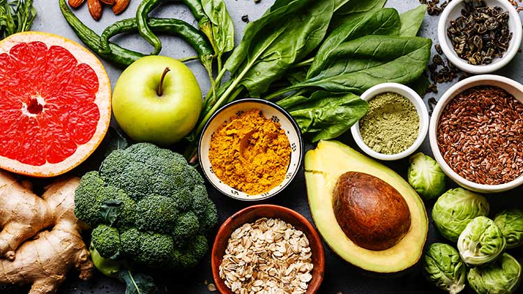 Vielfältige Lebensmittel wie Obst, Gemüse, Nüsse, Samen und Gewürze, darunter Avocado, Brokkoli, Blaubeeren und Mandeln.