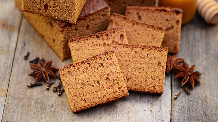 Mehrere Scheiben Lebkuchen auf Holzuntergrund mit Sternanis und Gewürznelken als Dekoration.