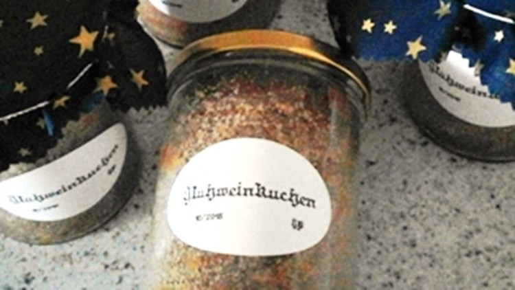 Fünf Gläser mit der Aufschrift „Schneekuchen“, teilweise mit blauen Stoffdeckeln und goldenen Sternen, stehen auf einer Fläche.