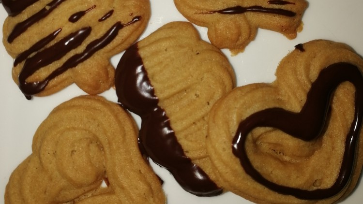 Sechs Butterplätzchen in verschiedenen Formen, teils mit dunkler Schokolade glasiert, auf einem weißen Teller.