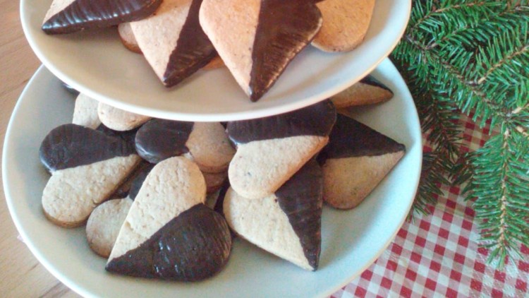 Zwei Etageren mit herzförmigen Keksen, teils mit Schokolade, daneben eine Tafel mit „mit Liebe gebacken“ und ein Tannenzweig.