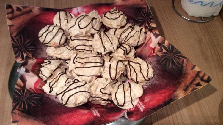 Mehrere helle Gebäckstücke mit Schokoladenstreifen liegen auf einem weihnachtlich bedruckten Servierteller.