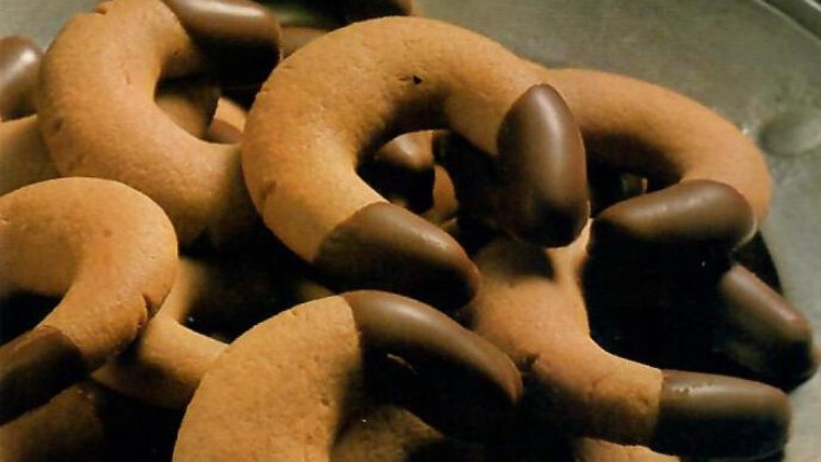 Mehrere Schoko-Kekse in Form von Hörnchen mit schokoladentauchten Enden liegen in einer metallischen Schale.