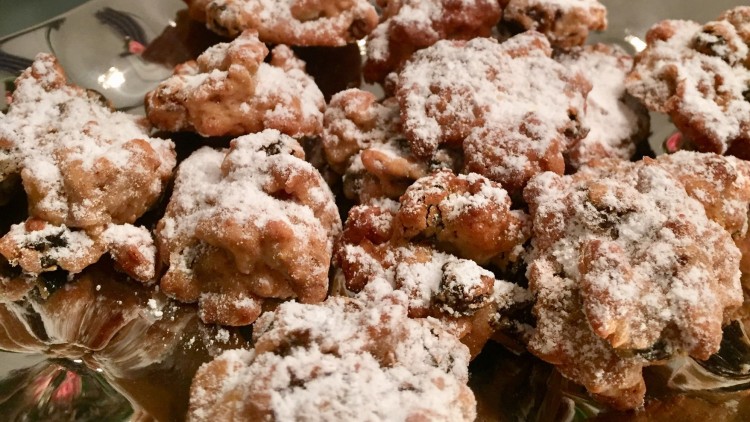 Plätzchen mit Rosinen und Puderzucker auf einem silbernen Teller, im Hintergrund weihnachtliche Dekoration mit Holz und Metall.