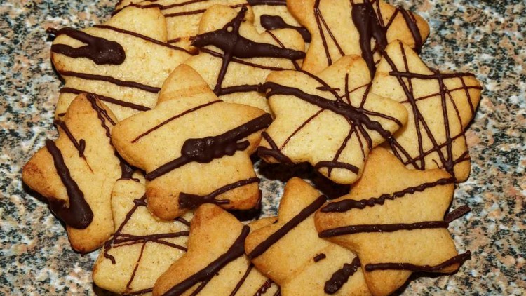 Sternförmige Plätzchen mit Zartbitterschokoladenlinien auf einer gemusterten Steinoberfläche.