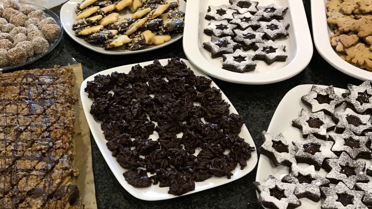 Verschiedene Platten und Schüsseln mit Weihnachtsplätzchen wie Sternen, Kipferln, Herzen, Schokohäufchen und Kokoskugeln.