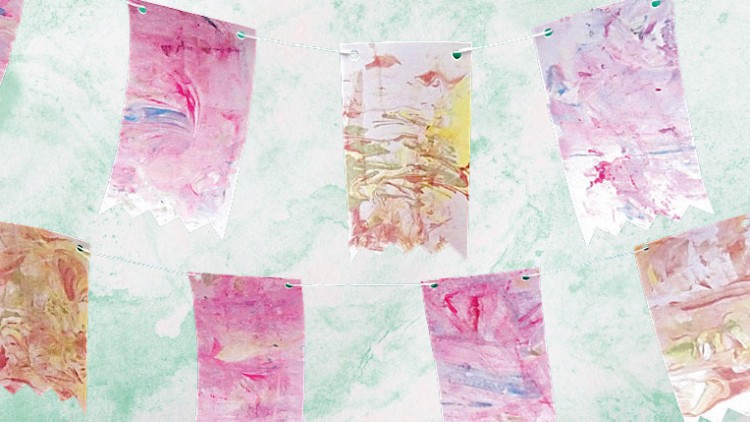 Bunte Wimpel mit marmorierten Mustern in Rosa, Weiß und Gelb hängen an Schnüren vor einem grün marmorierten Hintergrund.
