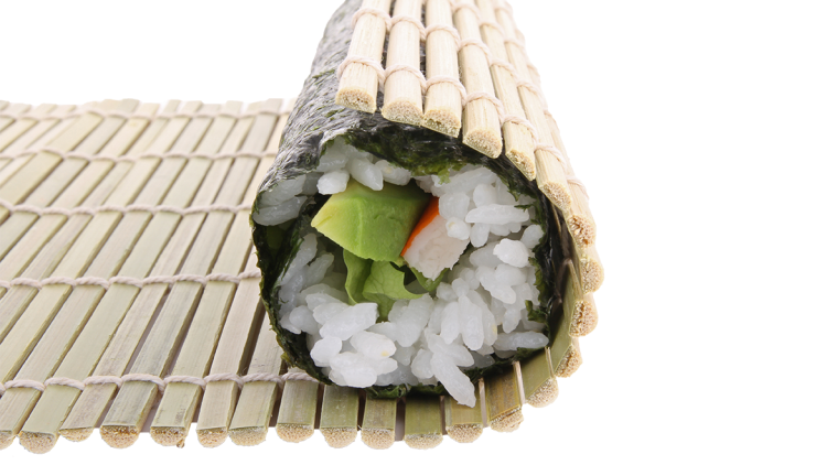 Gerolltes Sushi mit Nori-Algenblatt, Reis, Avocado, Karotte und Salat auf einer Bambusmatte.